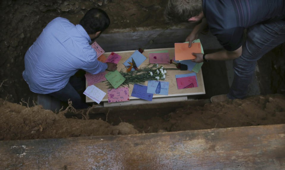 Men arrange personal notes on the coffin that contains the remains of 12-year-old Howard Jacob Miller Jr., at the cemetery in Colonia Le Baron, Mexico, Friday, Nov. 8, 2019, during a burial service for Rhonita Miller and four of her young children, who were murdered by drug cartel gunmen. The bodies of Miller and four of her children were taken in a convoy of pickup trucks and SUVS, on the same dirt-and-rock mountainous road where they were killed Monday, for burial in the community of Colonia Le Baron in Chihuahua state. (AP Photo/Marco Ugarte)