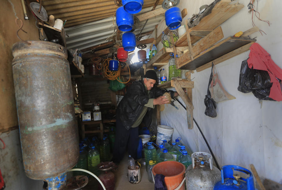 A Syrian displaced man Mohammed Zakaria, 53, who fled his Syrian hometown of Homs in 2012, works at his gas and oil shop which is at the entrance of his tent at a refugee camp, in Bar Elias, in eastern Lebanon's Bekaa valley, Friday, March 5, 2021. Nearly ten years later, the family still hasn't gone back and Zakaria is among millions of Syrians unlikely to return in the foreseeable future, even as they face deteriorating living conditions abroad. The Syrian conflict has resulted in the largest displacement crisis since World War II. (AP Photo/Hussein Malla)