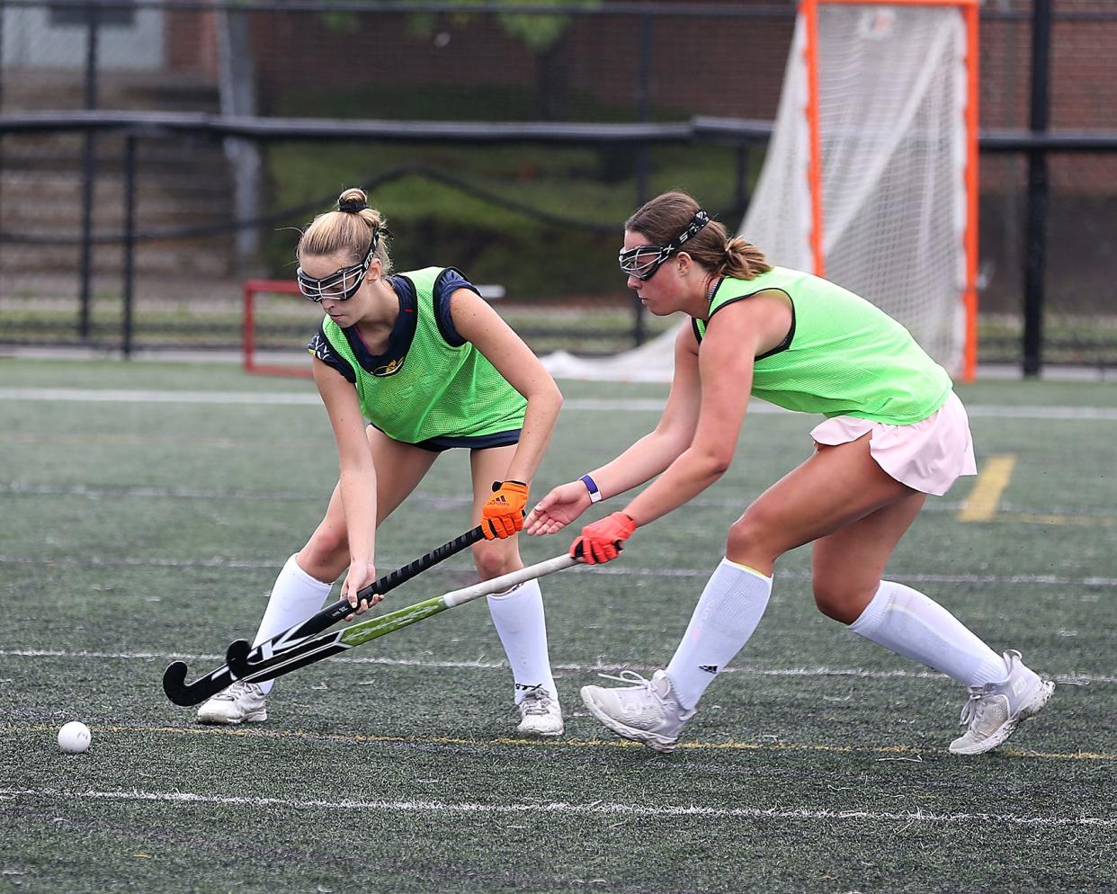 Hingham junior Stella Brazis and junior Anna Kiernan battle for the ball during a drill at field hockey practice at Hingham High School on Tuesday, Aug. 23, 2022.