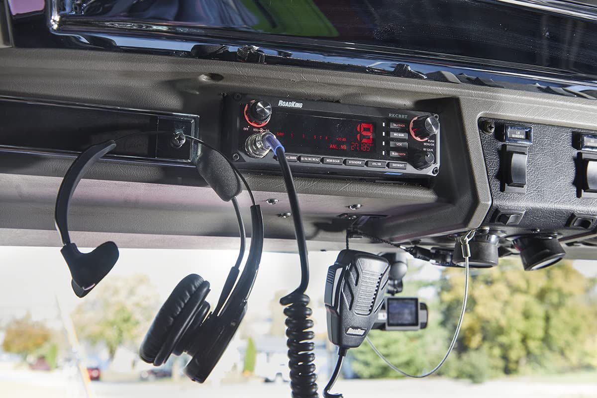 Black RoadKing RKCBBT Voice-Activated Hands-Free CB Radio hanging on dash of truck