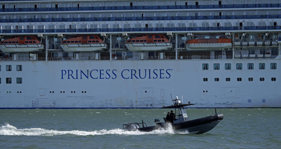FILE - In this Friday, March 13, 2020, file photo, an Oakland Police boat patrols the waters beside the Grand Princess cruise ship, which remains docked at the Port of Oakland in Oakland, Calif. Nearly 650 crew members of the Grand Princess have completed their 14-day quarantine, ending a month-long period of self-isolation that began when the cruise ship was struck with the coronavirus. The cruise line said the crew members can finally leave their staterooms Saturday, April 4, and roam around the ship as long as they wear personal protective equipment and stay at least six feet from each other. The ship will leave San Francisco Bay and sail out to sea for several days of routine marine operations. (AP Photo/Ben Margot, File)