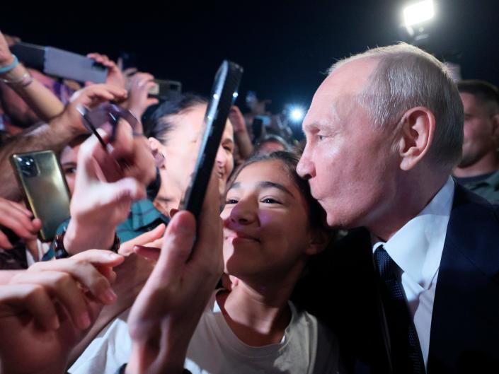 Russian President Vladimir Putin, right, poses for a selfie with local citizens