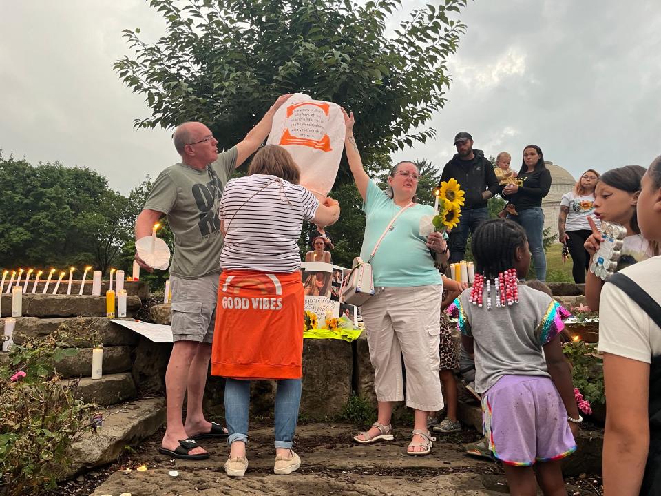 Holly Clapsaddle of Canton, right, holds up a cloth lantern in Sheridan's memory Thursday evening in Monument Park in Canton before she and two others released it into the sky.