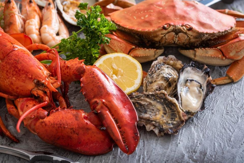 A plate of seafood including lobster, crab, oyster and mussels, with lemon slices.