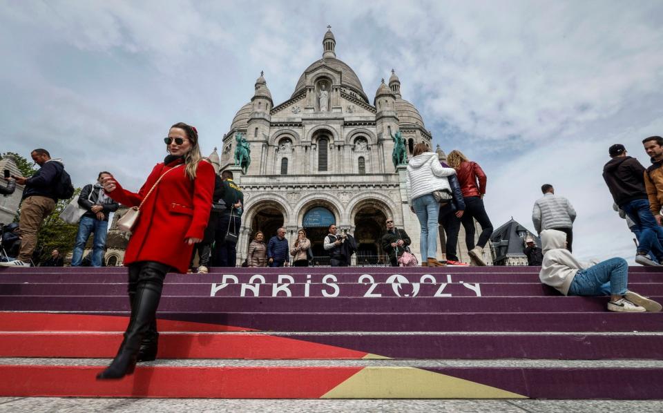 People walk down the stairs painted in the colours of the upcoming Paris 2024 Olympics in front of the Sacre Coeur Basilica on top of the Montmartre hill in Paris