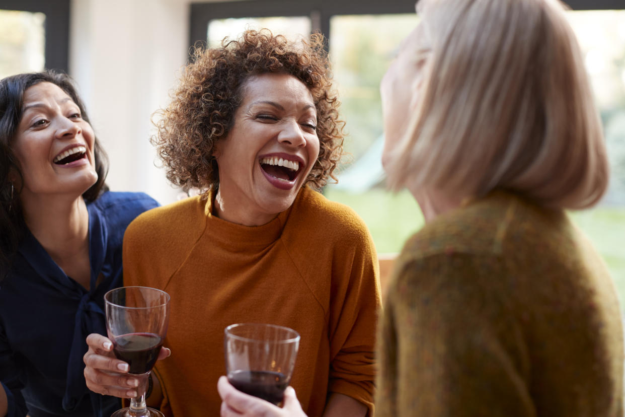 Group of female friends drinking wine and laughing (Getty Images)