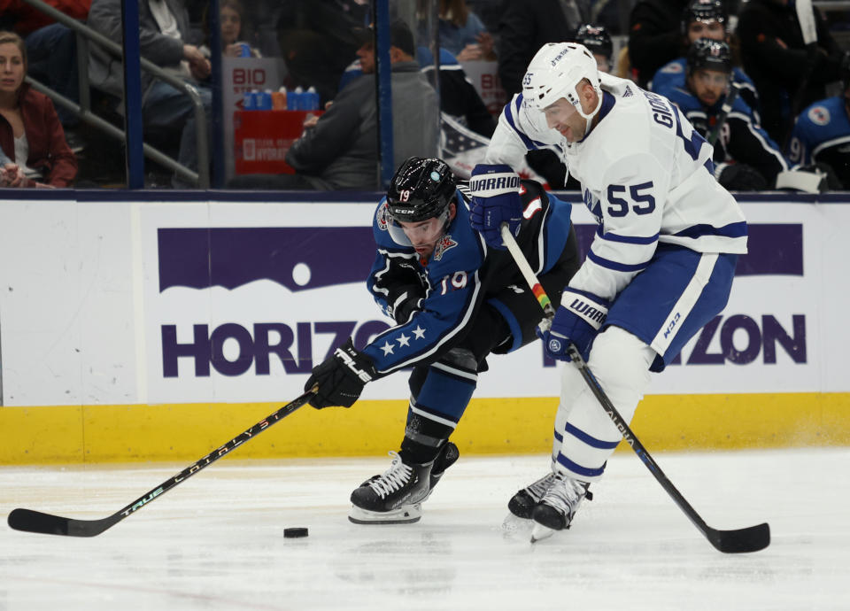 Columbus Blue Jackets forward Liam Foudy, left, reaches for the puck next to Toronto Maple Leafs defenseman Mark Giordano during the second period of an NHL hockey game in Columbus, Ohio, Friday, Feb. 10, 2023. (AP Photo/Paul Vernon)