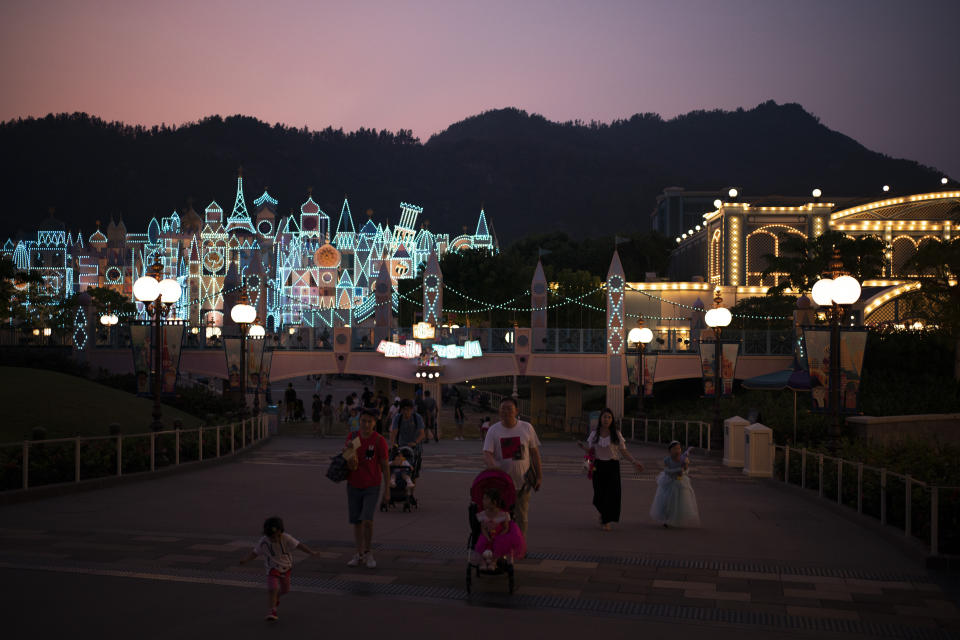 In this Oct. 11, 2019 photo, visitors walk at dusk in Hong Kong Disneyland in Hong Kong. The body-blow of months of political protests on Hong Kong’s tourism is verging on catastrophic for one of the world’s great destinations. Geared up to receive 65 million travelers a year, the city’s hotels, retailers, restaurants and other travel-oriented industries are suffering. But some intrepid visitors came specifically to see the protests and are reveling in deep discounts and unusually short lines at tourist hotspots.(AP Photo/Felipe Dana)