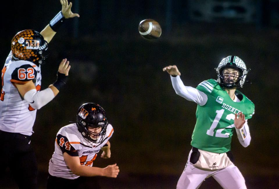 Eureka quarterback Jacob Morin (12) tosses a pass under pressure from Beardstown's Micah Wink (62) and Gunner Looker in the second half of their Class 3A first-round playoff game Friday, Oct. 28, 2022 in Eureka. The Hornets advanced with a 49-6 victory.