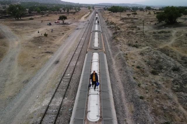 Migrants, mostly from Venezuela, walk on top of railroad cars as they get ready to continue their journey to the US border (Reuters)
