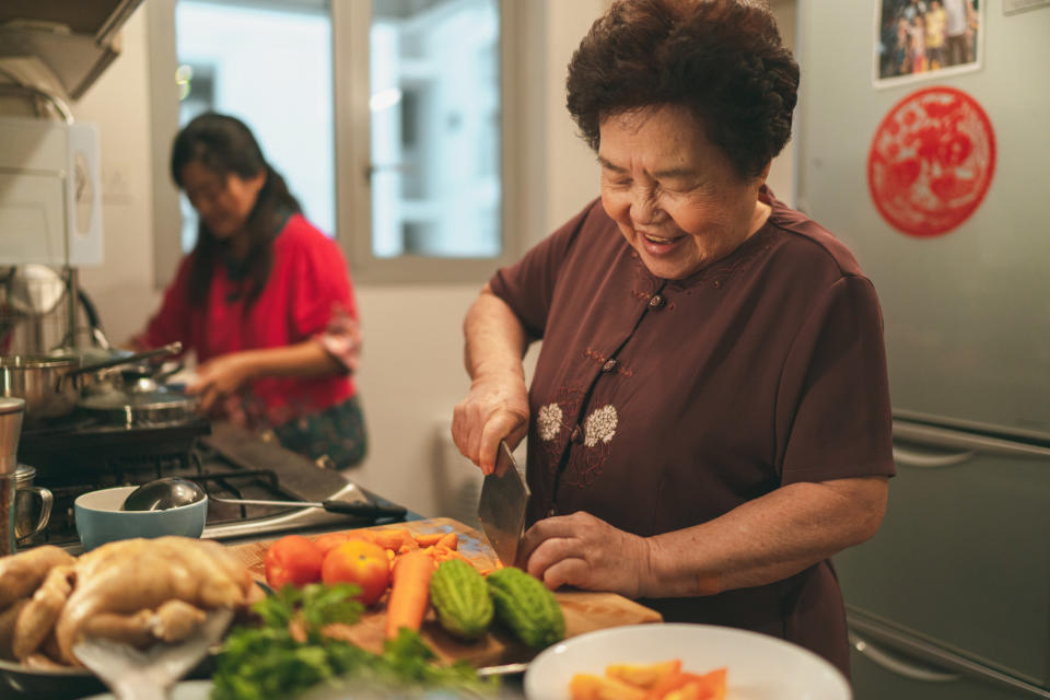 Asian grandmother chopping vegetables