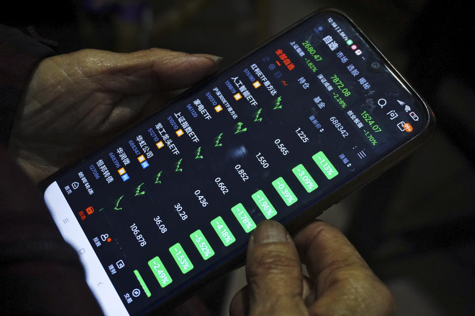 An investor holds a smartphone showing current shares prices at a brokerage house in Hangzhou in east China's Zhejiang province, Monday, Feb. 5, 2024. Chinese shares gyrated on Monday, sinking to 5-year lows, after stock market regulators sought to reassure jittery investors with a promise to crack down on stock price manipulation and "malicious short selling." (Chinatopix Via AP)