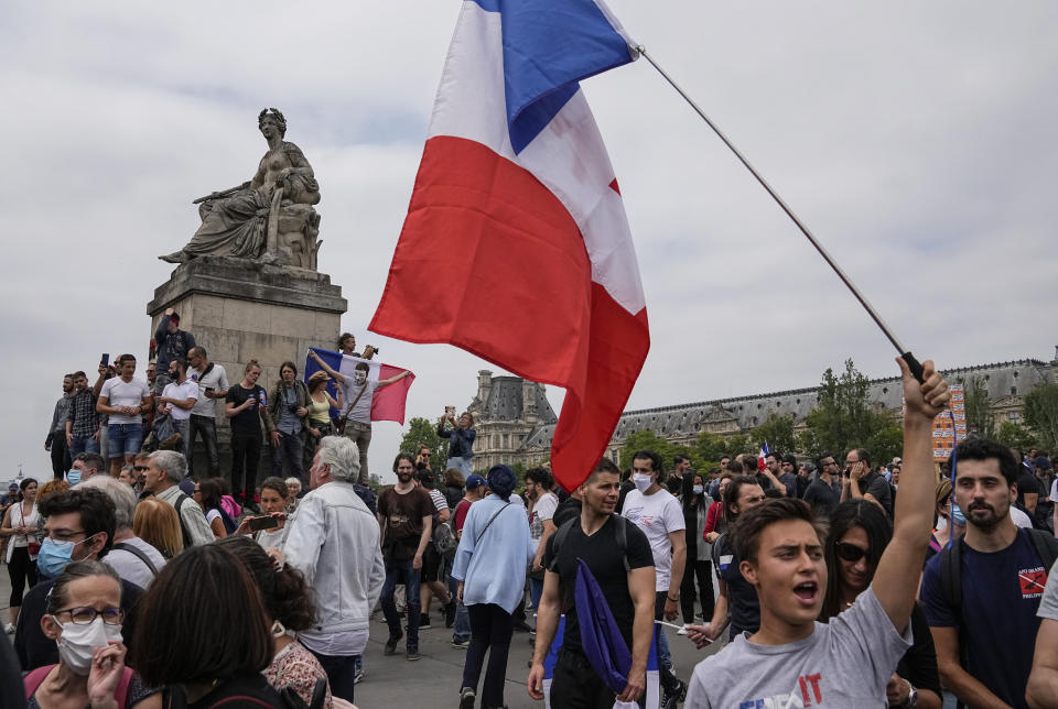 Anti-vaccine protester march with the French national flag during a rally in Paris, Saturday, July 17, 2021. Tens of thousands of people protested across France on Saturday against the government's latest measures to curb rising COVID-19 infections and drive up vaccinations in the country. (AP Photo/Michel Euler)