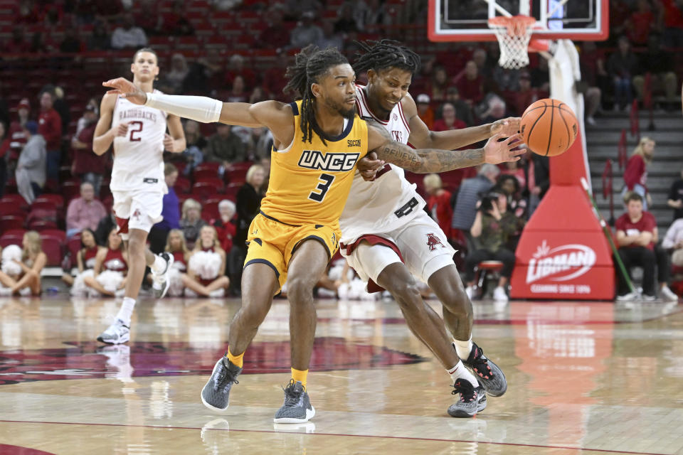 UNC Greensboro guard Kobe Langley (3) knocks the ball away from Arkansas guard Tramon Mark, right, during the second half of an NCAA college basketball game Friday, Nov. 17, 2023, in Fayetteville, Ark. (AP Photo/Michael Woods)