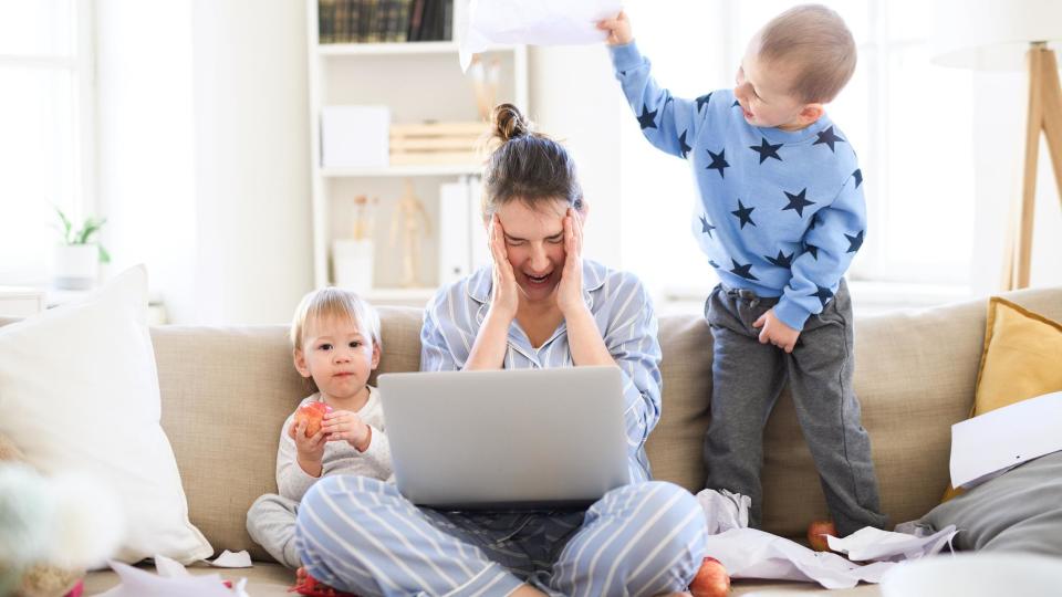 Una madre intenta trabajar con sus hijos alrededor.