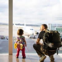 Vater und Tochter stehen am Flughafen vor einem Fenster