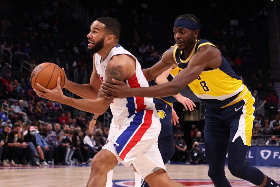 Cory Joseph of the Detroit Pistons gets grabbed on his way to the basket by Justin Holiday of the Indiana Pacers during the second half at Little Caesars Arena on November 17, 2021, in Detroit.