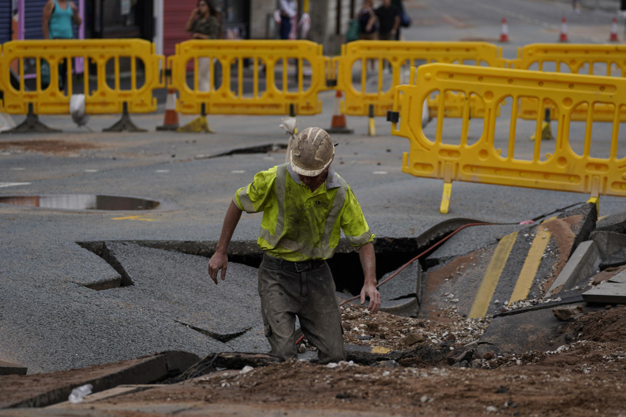 A United Utilities worker inspects a 4.5 metre (15ft) by six metre (20ft) sinkhole in Green Lane, Old Swan, Liverpool, caused by a suspected ruptured water main. Picture date: Saturday July 24, 2021.