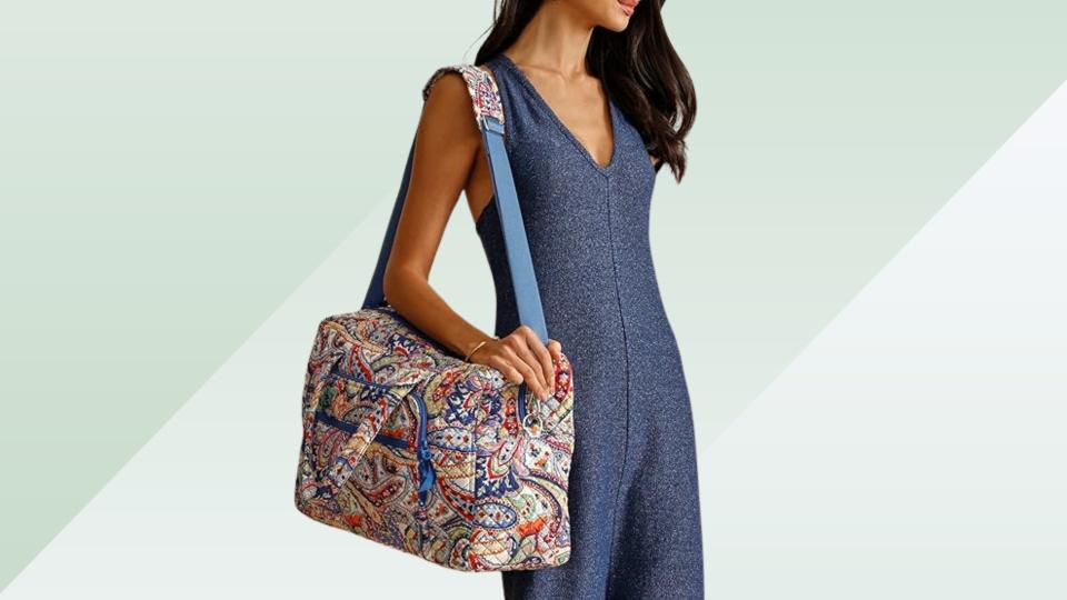 model carrying paisley vera bradley bag on green background. 