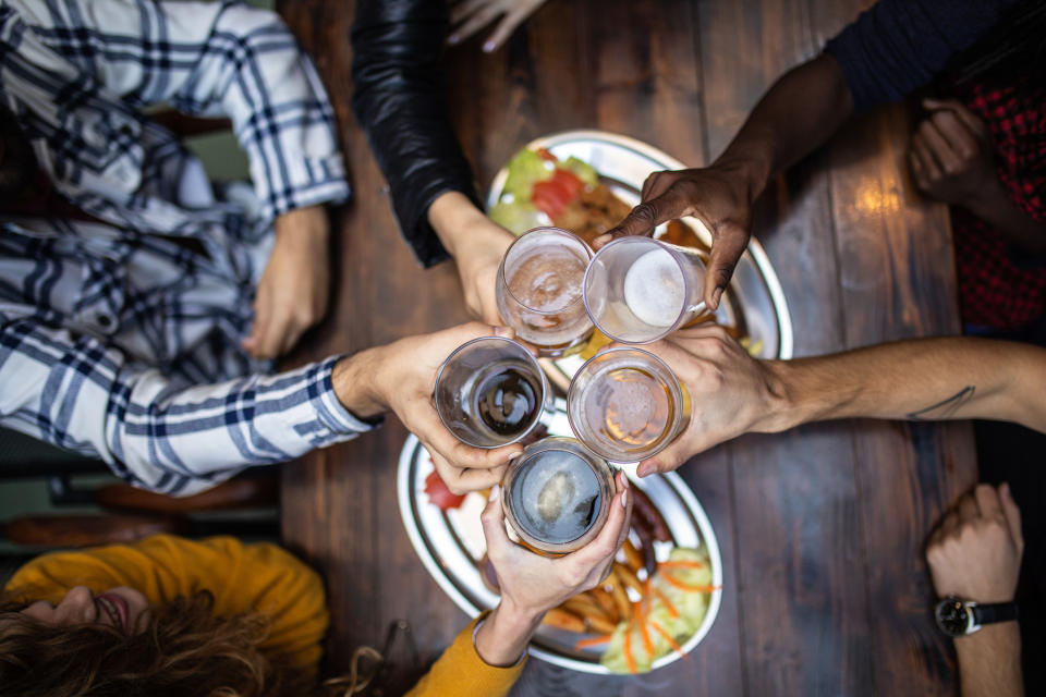 People clinking drinks at a bar.