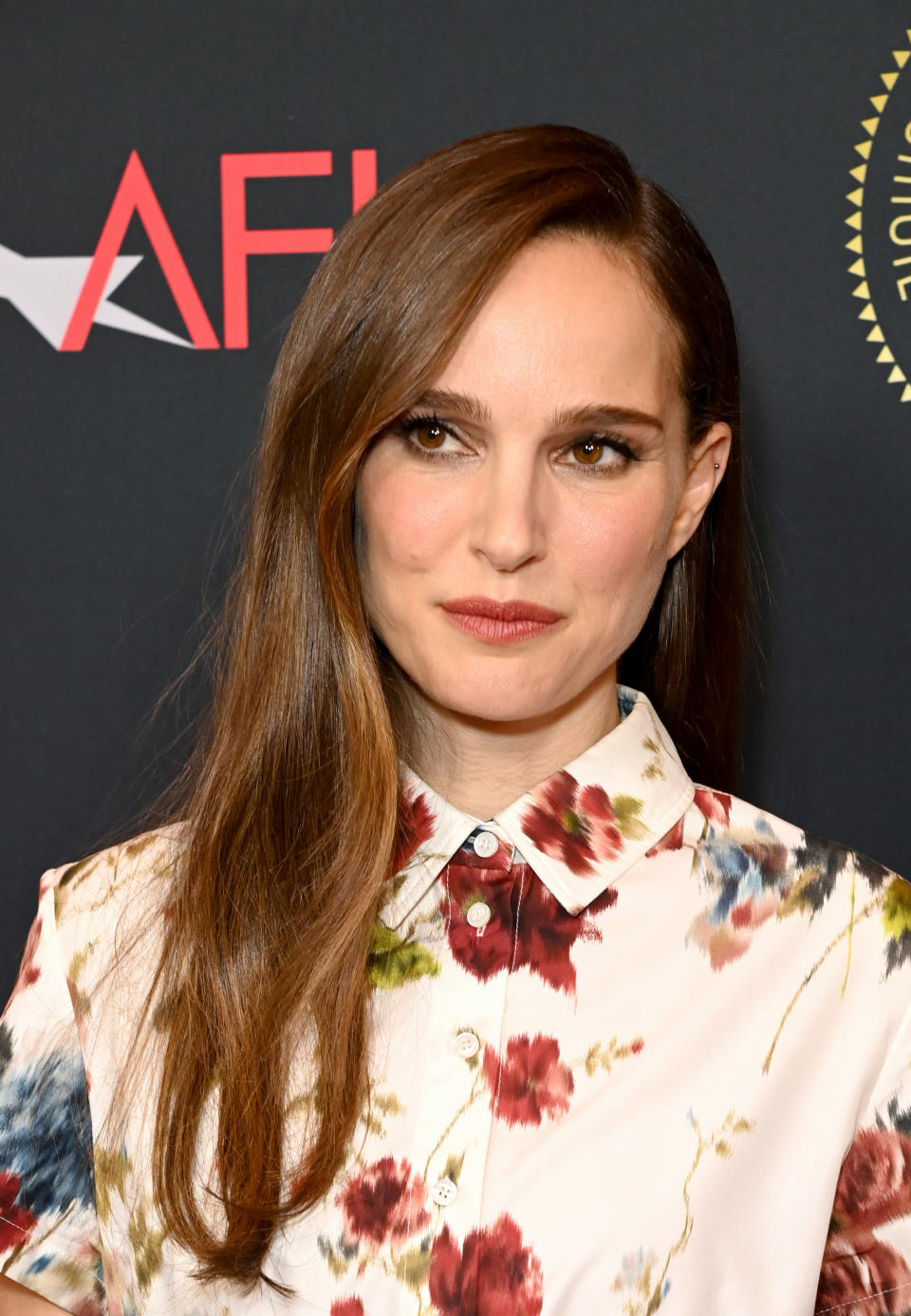 Natalie posing on the red carpet wearing a floral print shirt