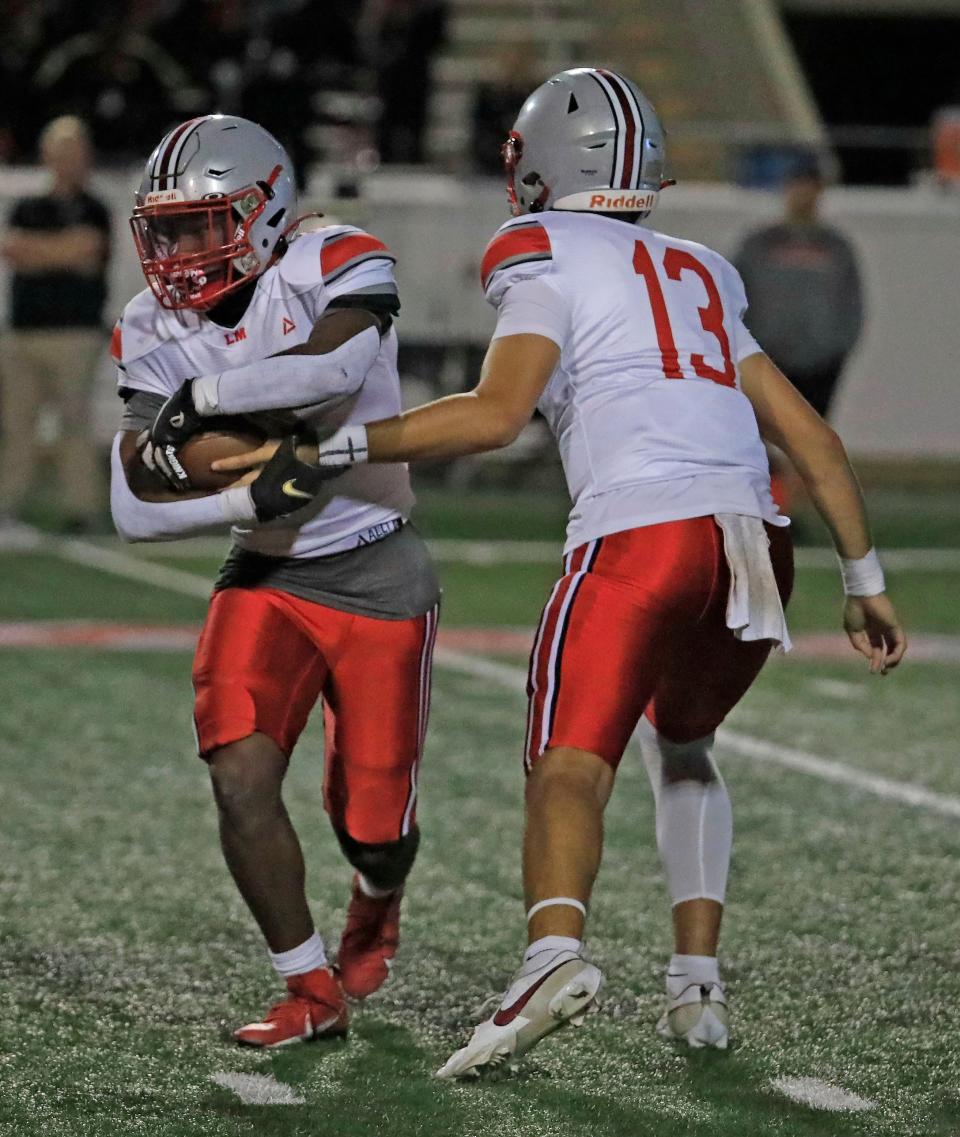 Noah Grubbs (13) Lake Marys Quarterback hands off the ball to Isaiah Thomas (4) Running Back during Friday nights game.