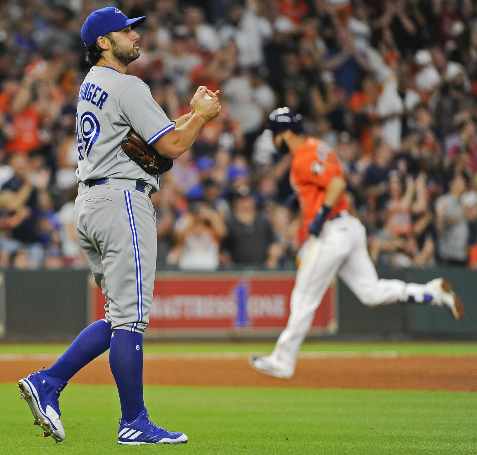 FILE - In this Aug. 4, 2017 file photo Toronto Blue Jays relief pitcher Mike Bolsinger, left, walks off the mound as Houston Astros' Marwin Gonzalez rounds the bases after hitting a three-run home run during the fourth inning of a baseball game in Houston. Bolsinger sued the Astros on Monday, Feb. 10, 2020 claiming their sign-stealing scheme contributed to a poor relief appearance August 2017 that essentially ended his big league career. (AP Photo/Eric Christian Smith, file)