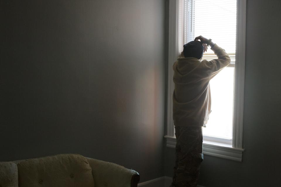 A man faces a window, away from the camera.