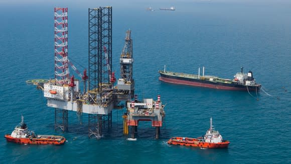 Offshore rig surrounded by several support vessels at sea.