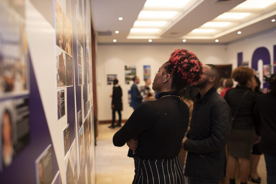 people viewing posters on a wall