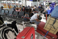 An overseas Filipino worker, who got quarantined as they arrived in the country weeks ago, rests beside his bags while they wait for their free ride back to their provinces on Tuesday, May 26, 2020 in Manila, Philippines. As about 24,000 Filipinos who lost their jobs abroad are being transported by land, sea or air to their provincial homes, the president warned local officials not to refuse them entry out of coronavirus fears. (AP Photo/Aaron Favila)