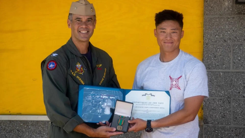 Captain Steve Djunaedi, Naval Air Station Oceana commanding officer, presents a Navy and Marine Corps Achievement medal to Aviation Electronics Technician Airman Michael Y. Yang for his actions as a lifeguard on June 30. (U.S. Navy)