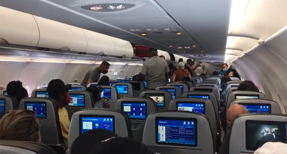 A still from a video shows passengers leaving a JetBlue aircraft because a toddler refused to wear a face mask.