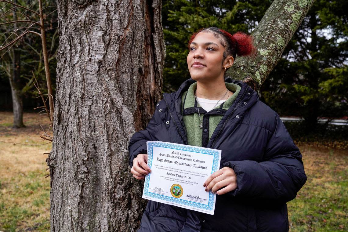 Kailani Taylor-Cribb holds her GED diploma outside her home in Asheville, N.C., on Tuesday, Jan. 31, 2023. She is among hundreds of thousands of students around the country who vanished from public school rolls during the pandemic and didn’t resume studies elsewhere. (AP Photo/Kathy Kmonicek)