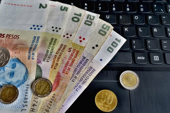 Argentine banknotes and coins on a keyboard.