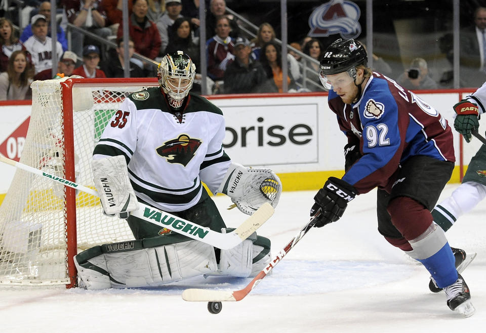 Colorado Avalanche left wing Gabriel Landeskog , right, of Sweden, tries to control the puck and shoot against Minnesota Wild goalie Darcy Kuemper, left, in the first period of Game 5 of an NHL hockey first-round playoff series on Saturday, April 26, 2014, in Denver. (AP Photo/Chris Schneider)