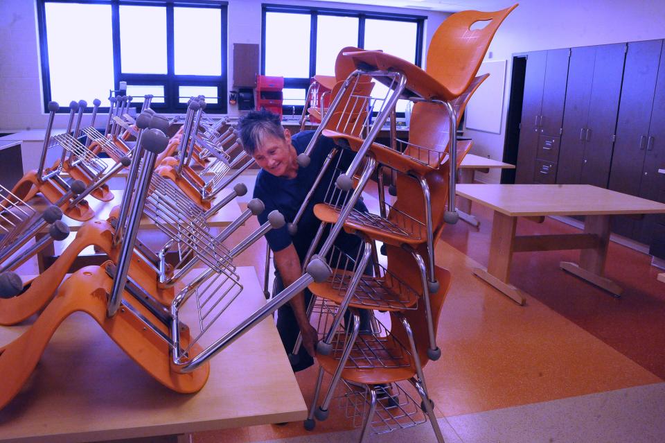 Dalton Elementary Middle School afternoon custodian Suzi Byall moves a stack of chairs so the finishing touches can be done to get a classroom ready.