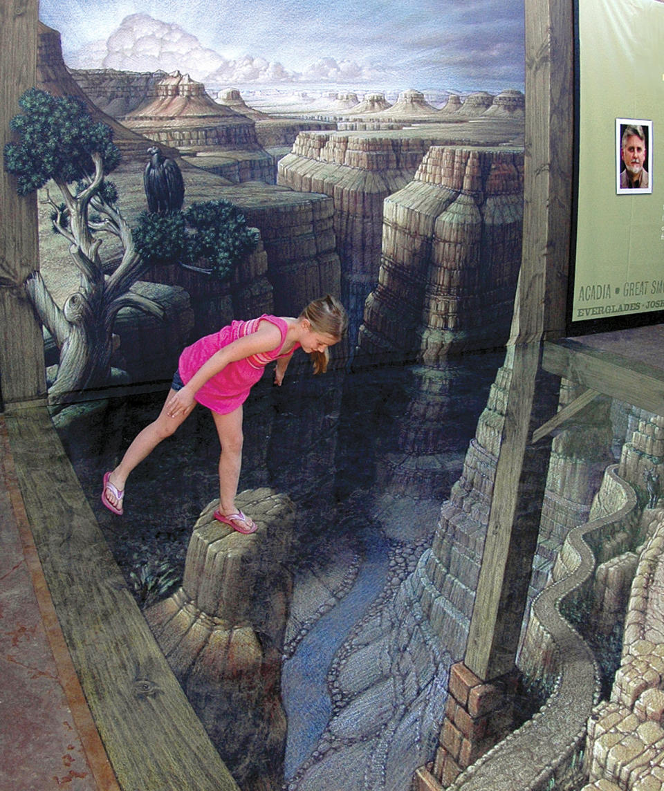 This June 15, 2012 photo released by the National Geographic Visitor Center at Grand Canyon shows an unidentified visitor examining the sidewalk artwork "Grand Canyon Illusion" by artist Kurt Wenner outside the National Geographic Visitor Center at the South Rim of the Grand Canyon near Tusayan, Ariz., in this handout photo made on June 15, 2012. The 3-D piece gives the illusion of being perched atop spires and starting down a winding trail that seemingly plunges into the depths of the massive gorge. (AP Photo/National Geographic Visitor Center at Grand Canyon, Joel Kramer)