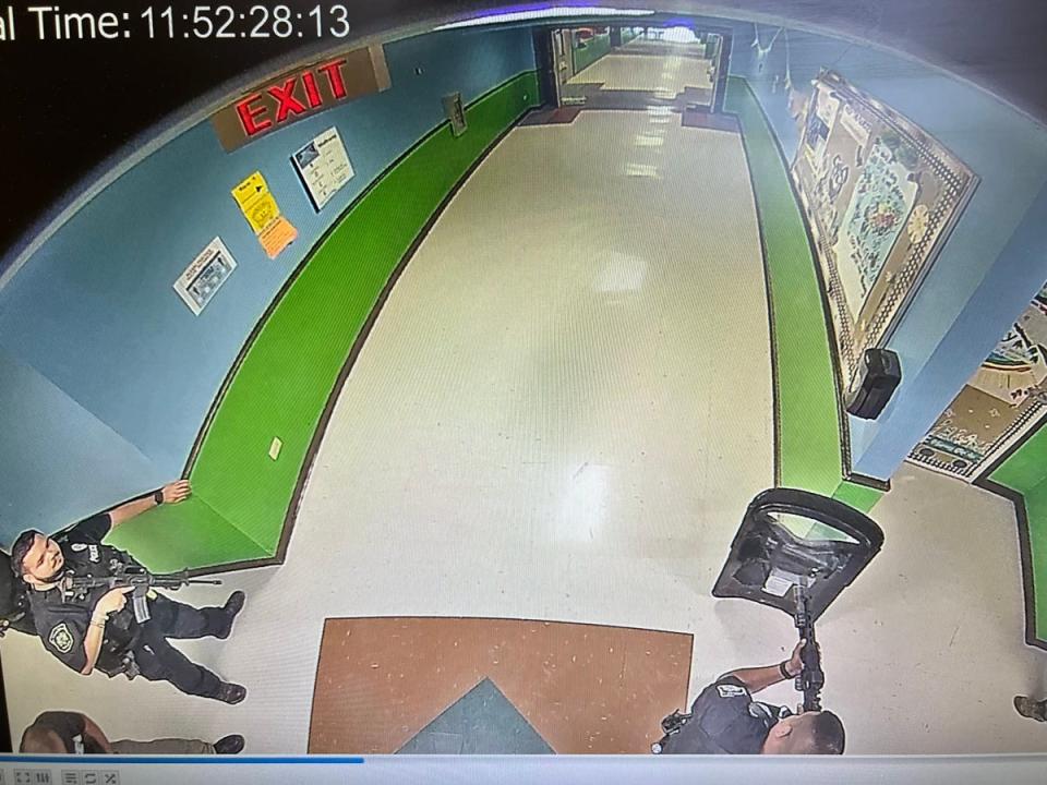 Police officers stand outside a classroom at Robb Elementary School in Uvalde, Texas, on 24 May, 2022, armed with rifles and a ballistic shield (Uvalde Consolidated Independent School District, via Austin America-Statesman/KVUE records request)