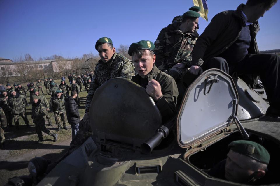In this photo taken on Saturday, April 5, 2014, Oleh Lyashko, center, leader of Ukrainian Radical Party and presidential candidate who supported the protests that ousted Russian-leaning president Viktor Yanukovych, gestures atop of a military vehicle during his visit to Ukrainian troops at their camp near Ukraine-Russian border outside Chernihiv, 140km (87 miles) northeast of Kiev, Ukraine. Ukraine's security service said Saturday it has detained a 15-strong armed gang planning to seize power in an eastern province on the border with Russia. (AP Photo/Osman Karimov)