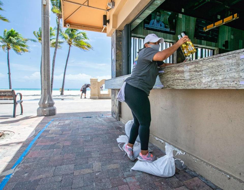 Kelly Santiago stands on sandbags as she prepares to serve customers at NickÕs Bar along the Hollywood Boardwalk in Hollywood Beach as Hurricane Isaias bears down on South Florida on Saturday, August 1, 2020.