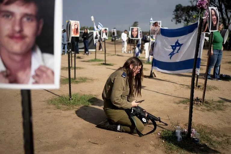 Una soldado israelí llora junto a un cartel que recuerda a una persona secuestrada el 7 de octubre en el ataque transfronterizo de Hamas contra el festival de música Nova