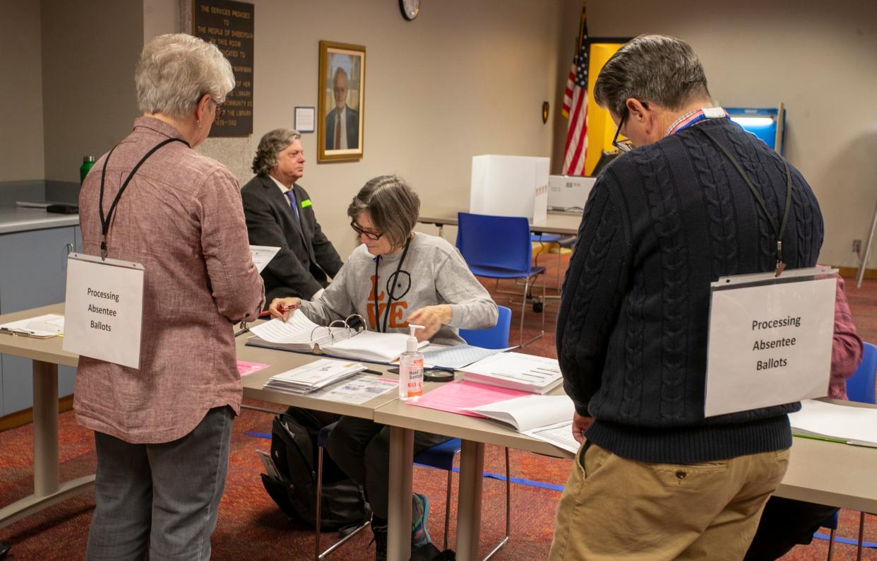 Poll workers tabulate absentee ballots Tuesday at the Mead Public Library.