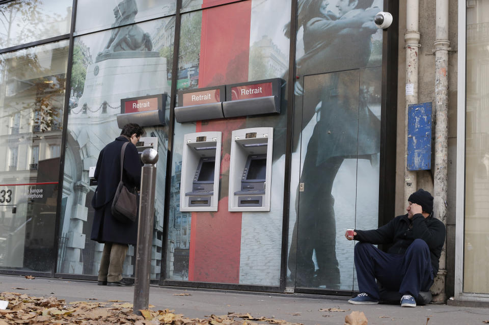 A homeless begs next to a bank of ATM's in Paris, Tuesday, Nov. 20, 2012 as France's government shrugged off the latest downgrade of its credit rating, saying Tuesday that it just needs time for reforms to the sluggish economy to take root. In a setback for President Francois Hollande's Socialist government, Moody's Investors Service stripped Europe's No. 2 economy of it of its prized AAA credit rating late Monday on concerns that its rigid labor market and exposure to Europe's financial crisis were threatening its prospects for economic growth. (AP Photo/Francois Mori)