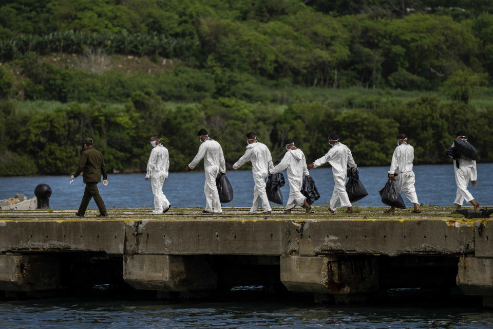 FILE - In this June 29, 2021 file photo, Cuban deportees walk to a COVID-19 control center where they will be quarantined after being handed over to the Cuban authorities at Orozco Bay in Artemisa, Cuba. The US Coast Guard repatriated 18 Cuban nationals that were found at sea attempting to migrate illegally into the United States. (AP Photo/Ramon Espinosa, File)