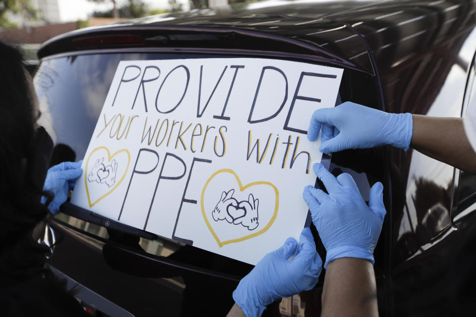 Signs are taped to a car before the start of a drive-by protest by Disney employees to demand a safe reopening amid the coronavirus pandemic Saturday, June 27, 2020, in Anaheim, Calif. Workers are demanding regular testing, stricter cleaning protocols and higher staffing levels. Disney had originally proposed reopening on July 17th but announced this week it was postponing. (AP Photo/Marcio Jose Sanchez)