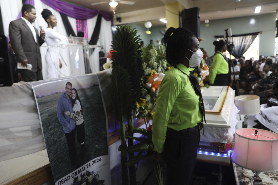 A photograph of Davy and Natalie Lloyd hangs during the funeral of their mission director Judes Montis, all three killed by gangs, in Port-au-Prince, Haiti, Tuesday, May 28, 2024. The Lloyds are a married couple in their early 20s who were with Montis when gunmen ambushed them on Thursday night, May 23, as they left a youth group activity held at a local church. (AP Photo/Odelyn Joseph)