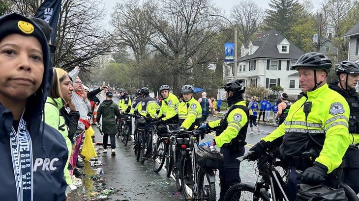 Group of cheering spectators gets blocked by police in green jackets and bikes