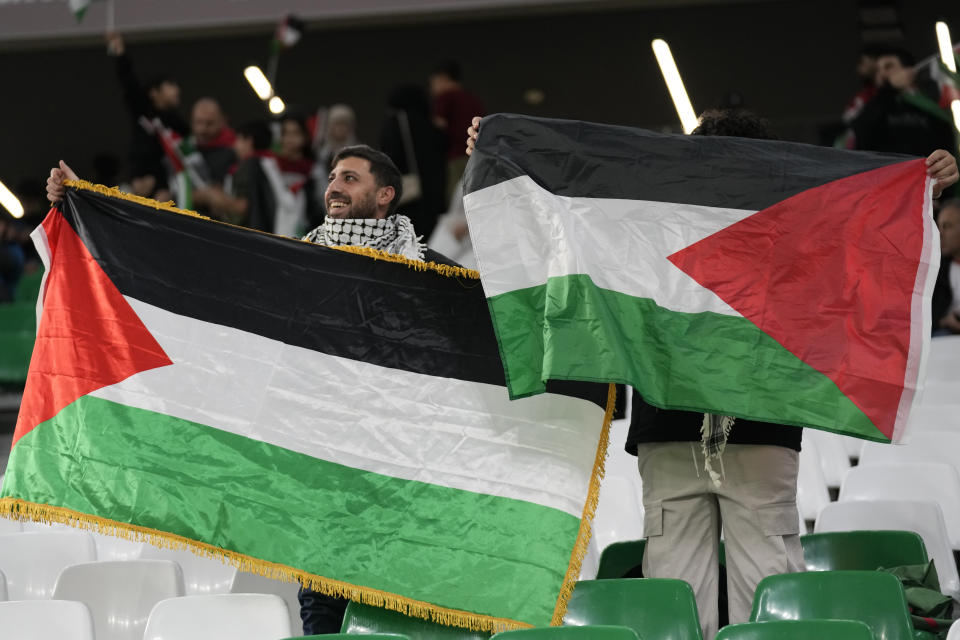 Fans hold Palestinian flags ahead of the Asian Cup Group C soccer match between Iran and Palestine at the Education City Stadium in Al Rayyan, Qatar, Sunday, Jan. 14, 2024. (AP Photo/Aijaz Rahi)