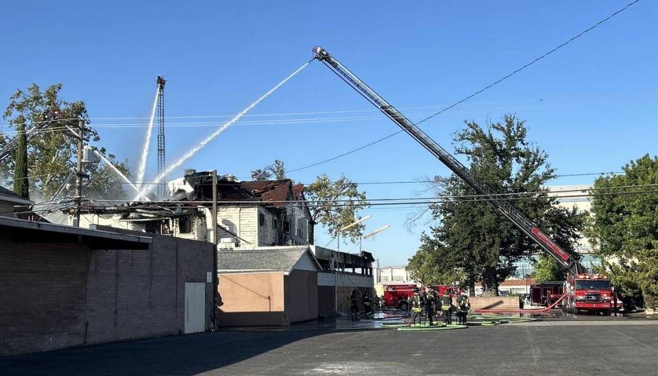 Los bomberos trabajan para extinguir las llamas en el antiguo edificio de Franklin and Downs Funeral Homes, en la esquina de la 12th y la G, en el centro de Modesto, el martes 16 de julio de 2024 por la mañana.